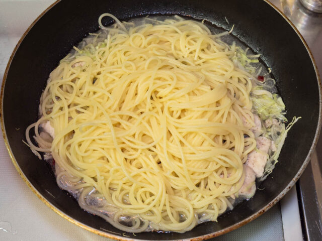 茹で上がったパスタをソースのフライパンに合わせた写真