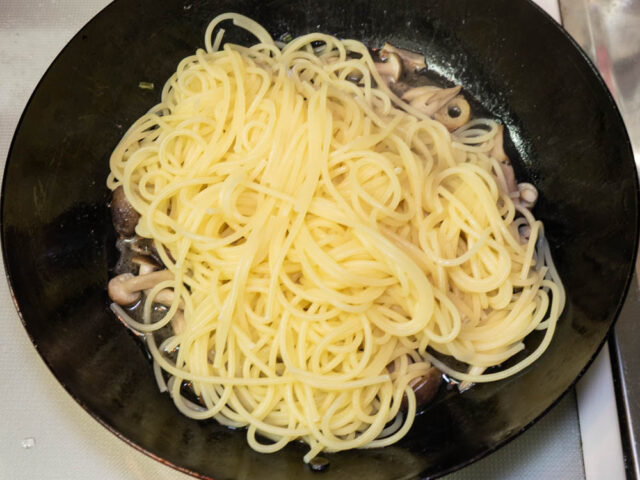 茹で上がったパスタをソースのフライパンに合わせた写真