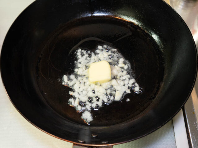 フライパンにサラダ油を熱して、ニンニクとバターを加えた写真