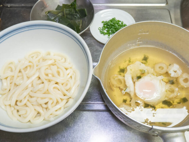 丼に移したうどん、鍋につくったつゆ、わかめ、細ねぎを並べた写真