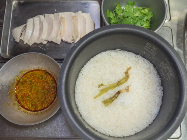炊き上がったご飯、鶏肉、タレ、パクチーの葉を並べた写真