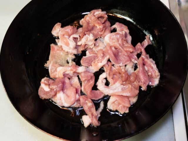フライパンにサラダ油を熱して、豚肉を加えた写真