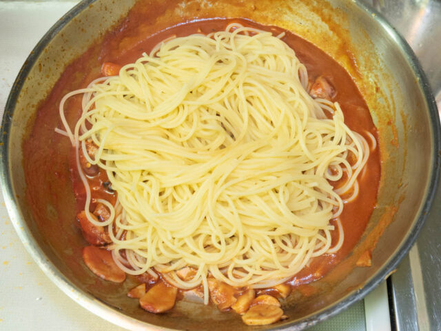 茹で上がったパスタをソースのフライパンに合わせた写真