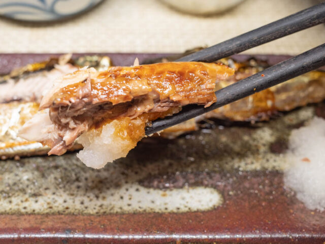秋刀魚の塩焼きを箸で持ち上げた写真