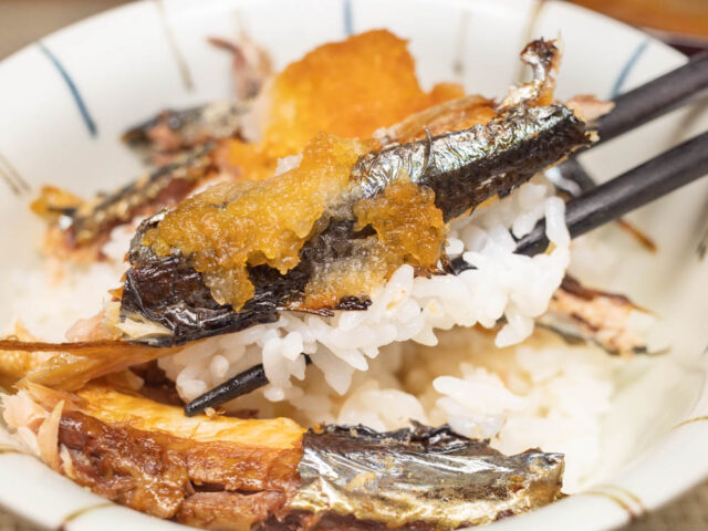 焼き秋刀魚と大根おろし、ご飯を箸で持ち上げた写真