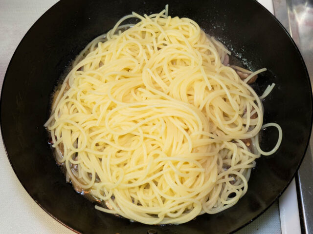 茹で上がったパスタをソースのフライパンに合わせた写真
