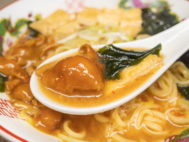 なめこ、わかめ、油揚げとスープをレンゲですくった写真