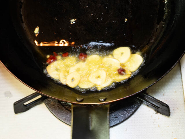 フライパンにオリーブオイル、ニンニク、唐辛子を入れて弱火で加熱する写真