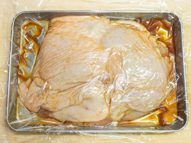 ラップでふたをして鶏肉を調味料につける写真