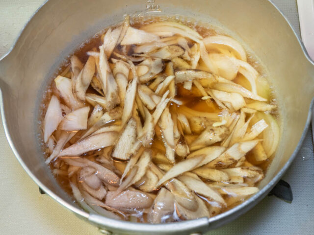 鍋に水、醤油、酒、ダシダ、ごぼう、玉ねぎを入れて煮る写真