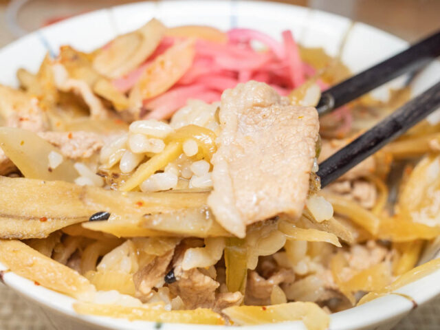 ご飯と豚肉を箸で持ち上げた写真