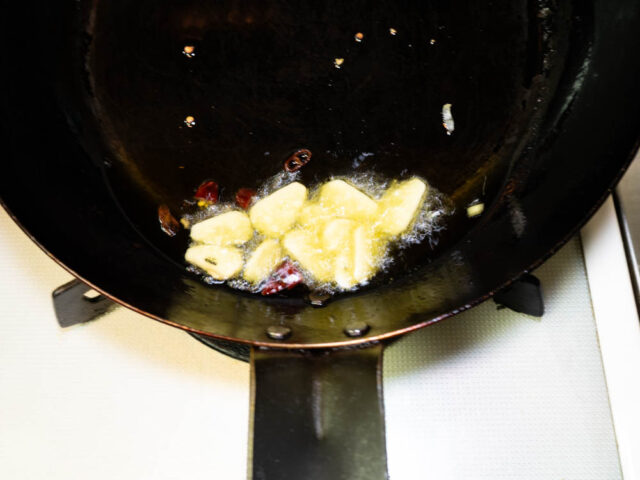 フライパンにオリーブオイル、ニンニク、唐辛子を入れて弱火で加熱する写真