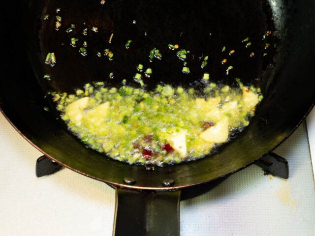 フライパンにオリーブオイル、ニンニク、唐辛子、パクチーを入れて弱火で加熱する写真
