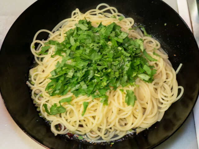 フライパンに茹で上がったパスタと刻んだパクチーを加えた写真