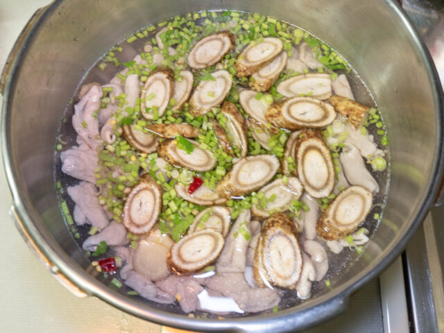 圧力鍋に、もつ、ごぼう、パクチー、ニンニク、唐辛子、水を入れた写真