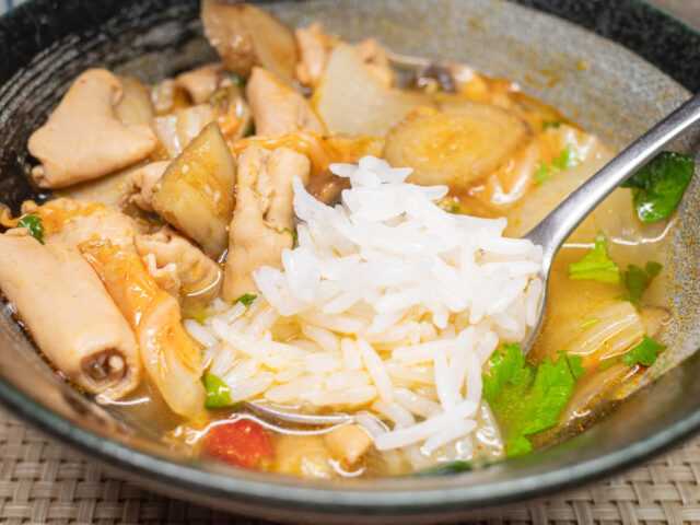 スプーンにのせたご飯をもつ煮にひたす写真