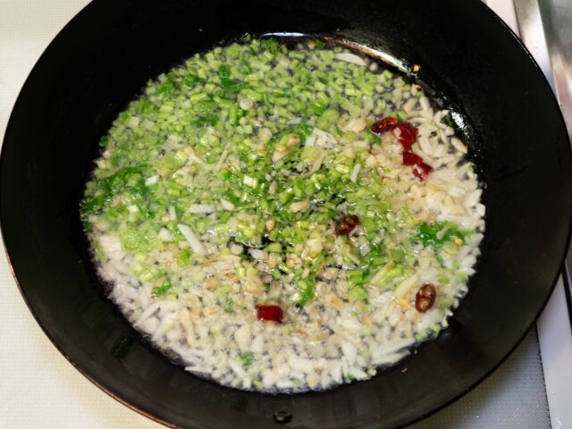 フライパンにサラダ油、ニンニク、唐辛子、刻んだパクチーを加えて加熱する写真