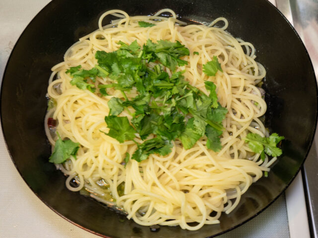 ソースのフライパンに、茹で上がったパスタと刻んだパクチーを加えた写真