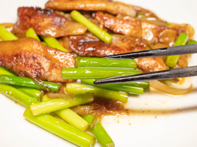 ニンニクの芽を箸で持ち上げた写真