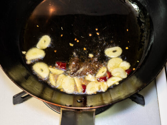 フライパンにオリーブオイル、ニンニク、唐辛子を入れて弱火で加熱し、アンチョビを加えた写真