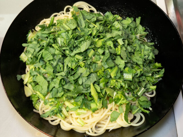 ソースのフライパンに茹で上がったパスタと春菊をあわせた写真