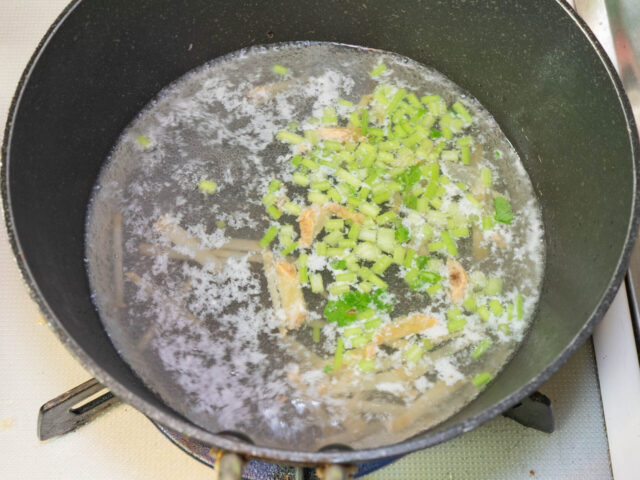 鍋に鶏の茹で汁、生姜、パクチーの茎を入れて火にかけた写真