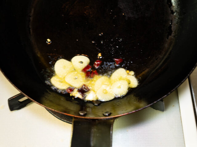 フライパンにオリーブオイル、ニンニク、唐辛子を入れて弱火で加熱する写真