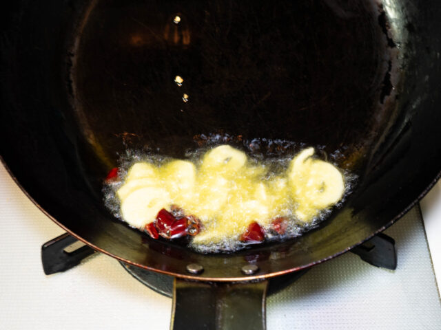 フライパンにオリーブオイル、ニンニク、唐辛子を入れて弱火で加熱する写真