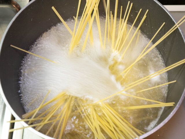 鍋にお湯を沸かし、塩を適量溶かしてからパスタを加えた写真