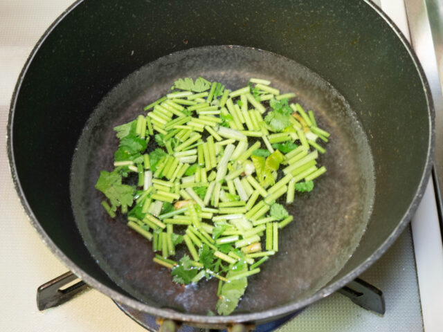 鍋にお湯を沸かし、パクチーの茎を加えた写真