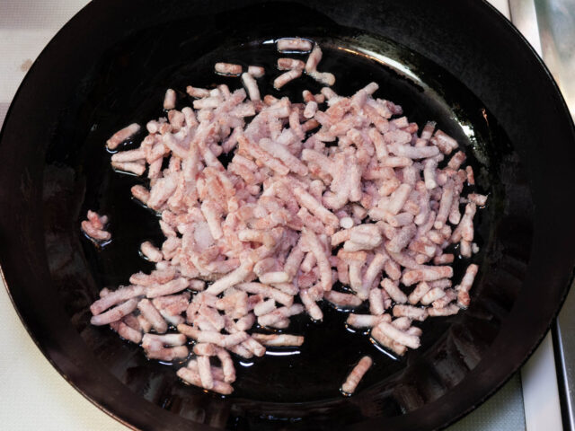 フライパンにサラダ油を熱して、ひき肉を加えた写真