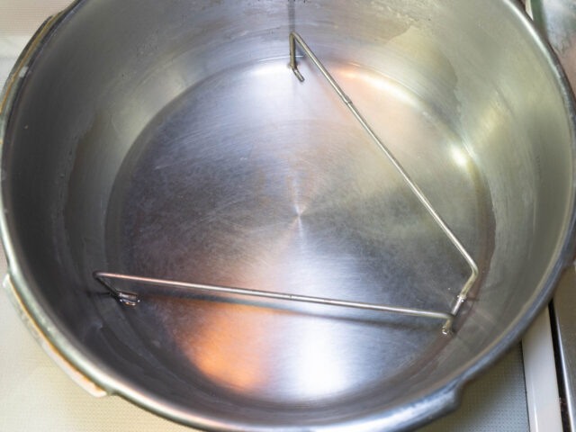 圧力鍋に蒸すための水と三脚を入れた写真