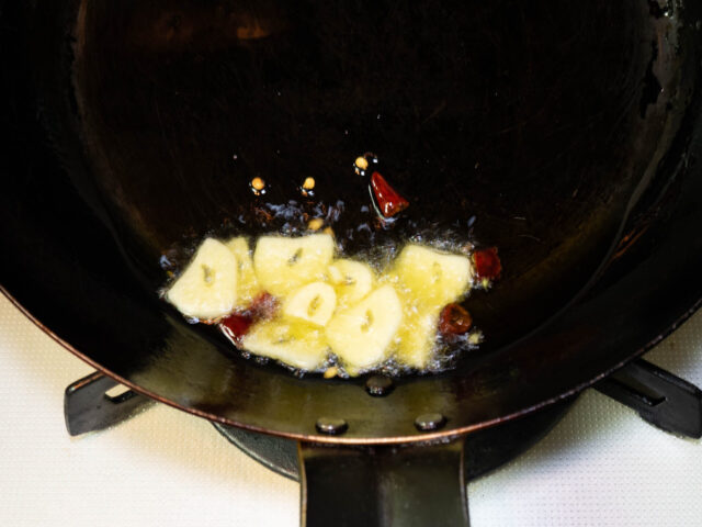 フライパンにオリーブオイル、ニンニク、唐辛子を入れて弱火で加熱する写真