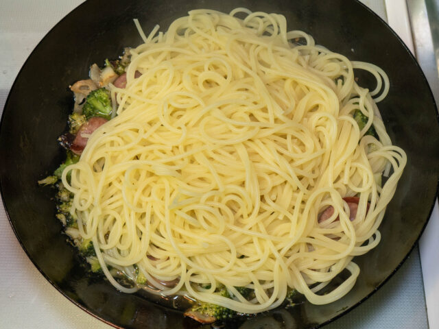 茹で上がったパスタをソースのフライパンにあわせた写真