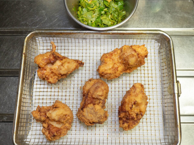 揚げた唐揚げと、つけダレであえたパクチーの写真