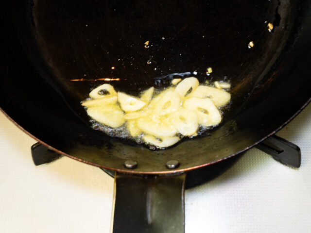 フライパンにオリーブオイルとニンニクを入れて、弱火で加熱する写真