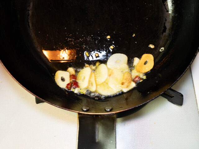 フライパンにオリーブオイル、ニンニク、唐辛子を入れて弱火で加熱する写真