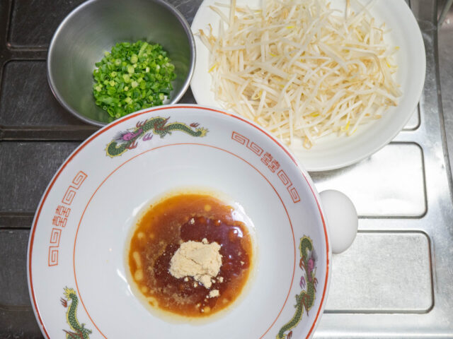 スープを入れた丼、もやし、刻みねぎの写真