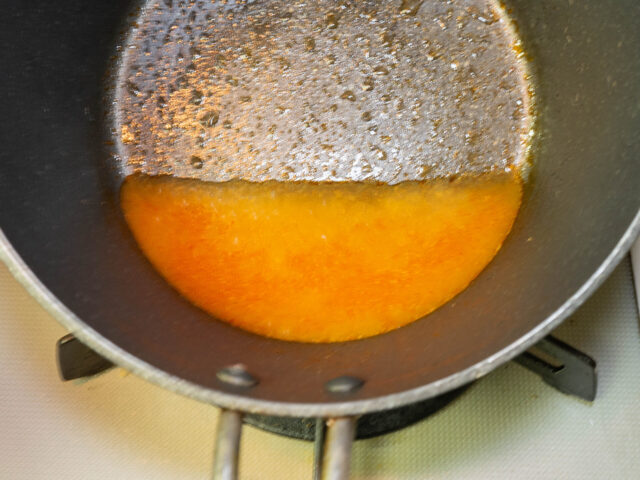 鍋に鶏の茹で汁とトムヤムクンペーストを入れて溶かす写真