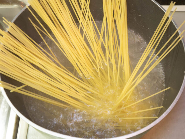 鍋にお湯を沸かし、塩を適量溶かしてからパスタを加えた写真