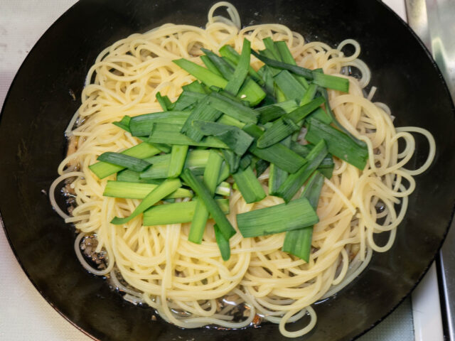 ソースのフライパンに茹で上がったパスタとニラを加えた写真