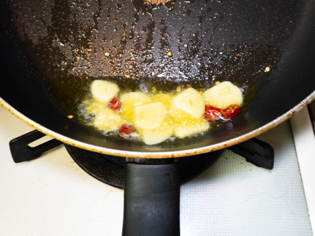 フライパンにオリーブオイル、ニンニク、唐辛子を入れて弱火で加熱する写真