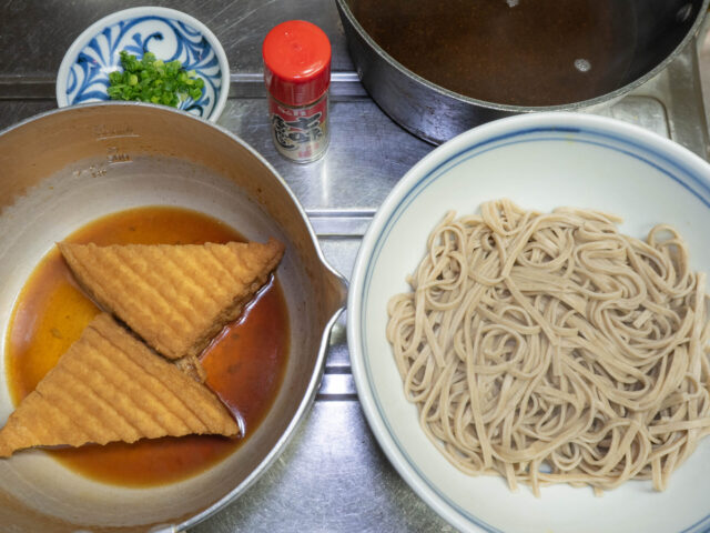 丼に入れた蕎麦、煮しめた厚揚げ、蕎麦つゆの写真