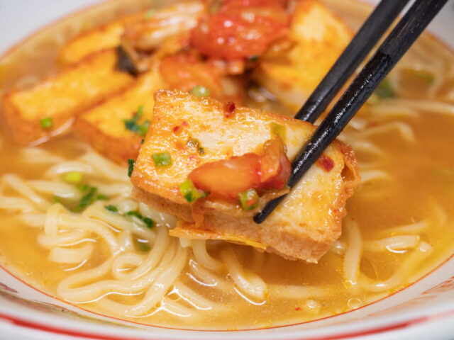 油揚げのキムチ炒めを箸で持ち上げた写真