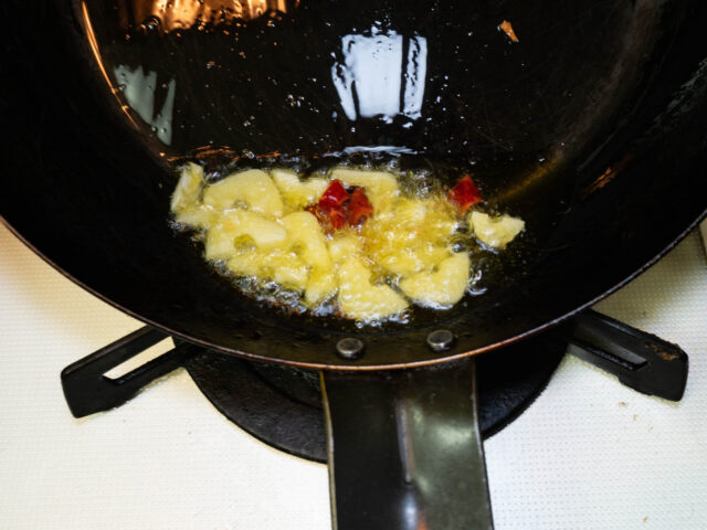 フライパンにオリーブオイル、ニンニク、唐辛子を入れて弱火で加熱する写真