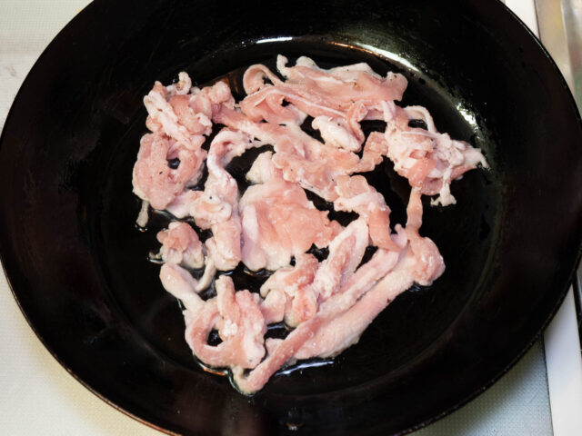 フライパンにサラダ油を熱した、豚肉を加えた写真