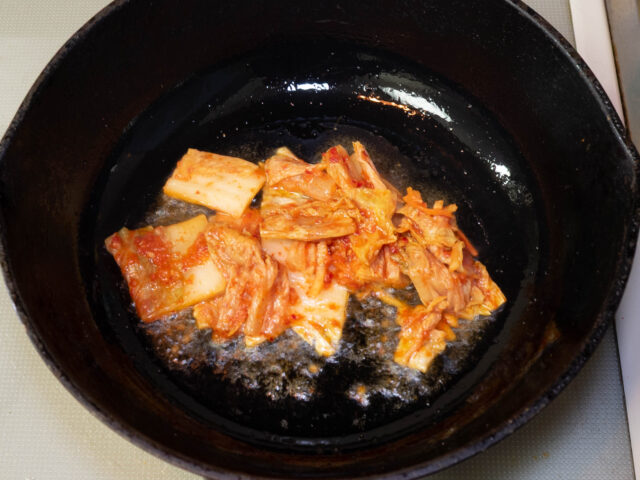 鍋にごま油を熱してキムチを加えた写真