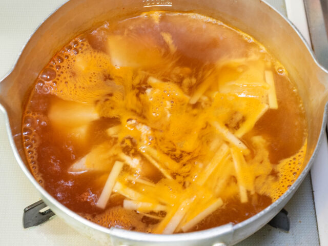 粉末スープ、キムチの素、豚肉を加えて煮る写真