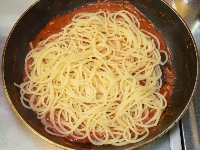 ソースのフライパンに茹で上がったパスタをあわせた写真