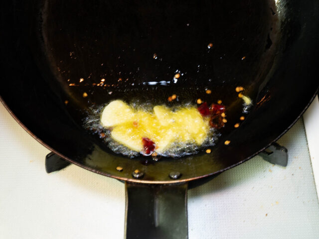 フライパンにオリーブオイル、ニンニク、唐辛子を入れて弱火で加熱する写真